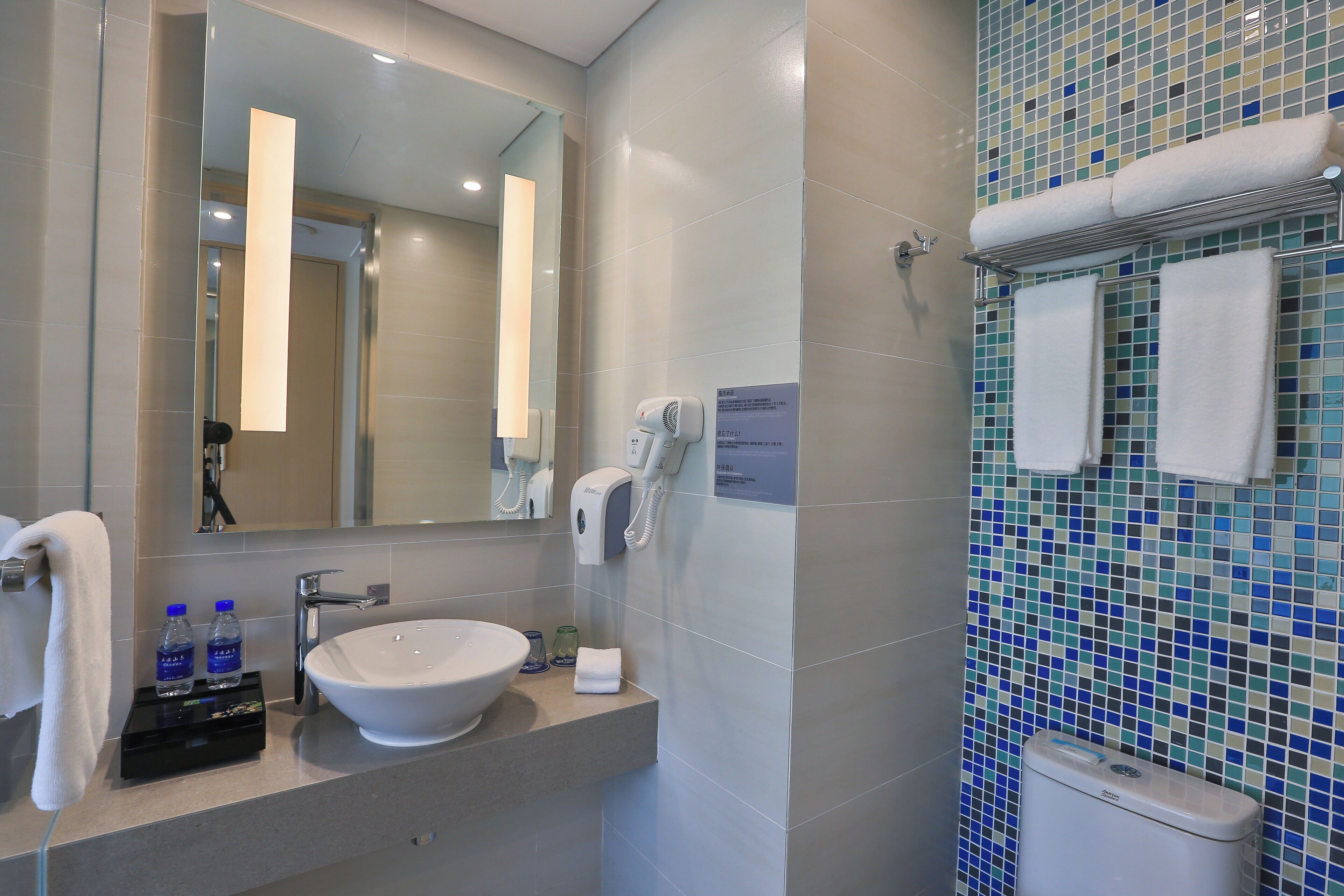 A bathroom with a sink, mirror, towel rack, and a toilet.
