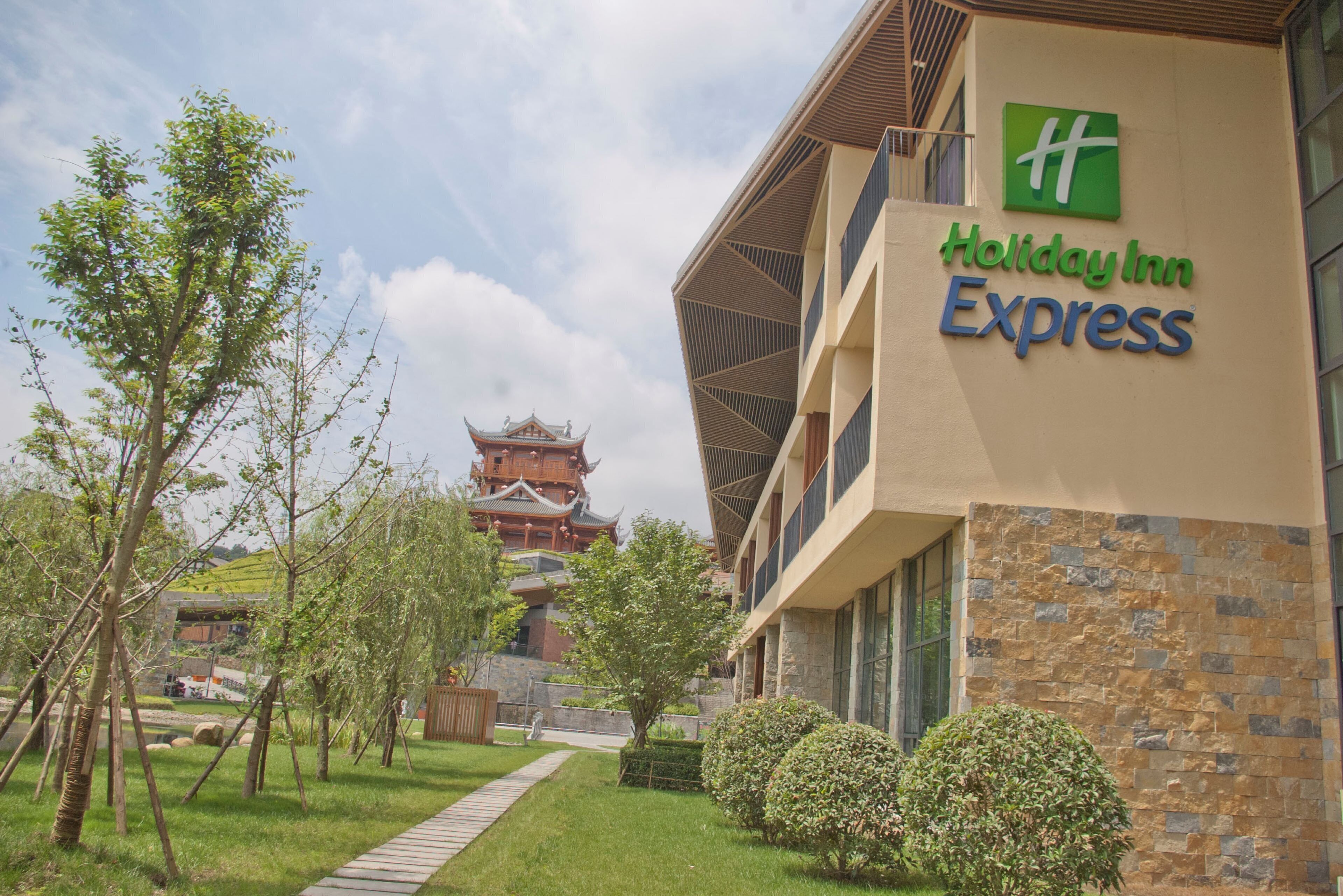 Um edifício Holiday Inn Express com uma estrutura tradicional em estilo pagoda ao fundo.