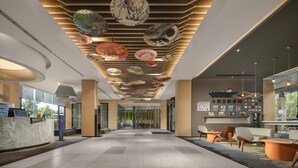 A modern hotel lobby with a reception desk, seating area, and decorative ceiling fans. - Holiday Inn Express Emei Mountain by IHG (Leshan)