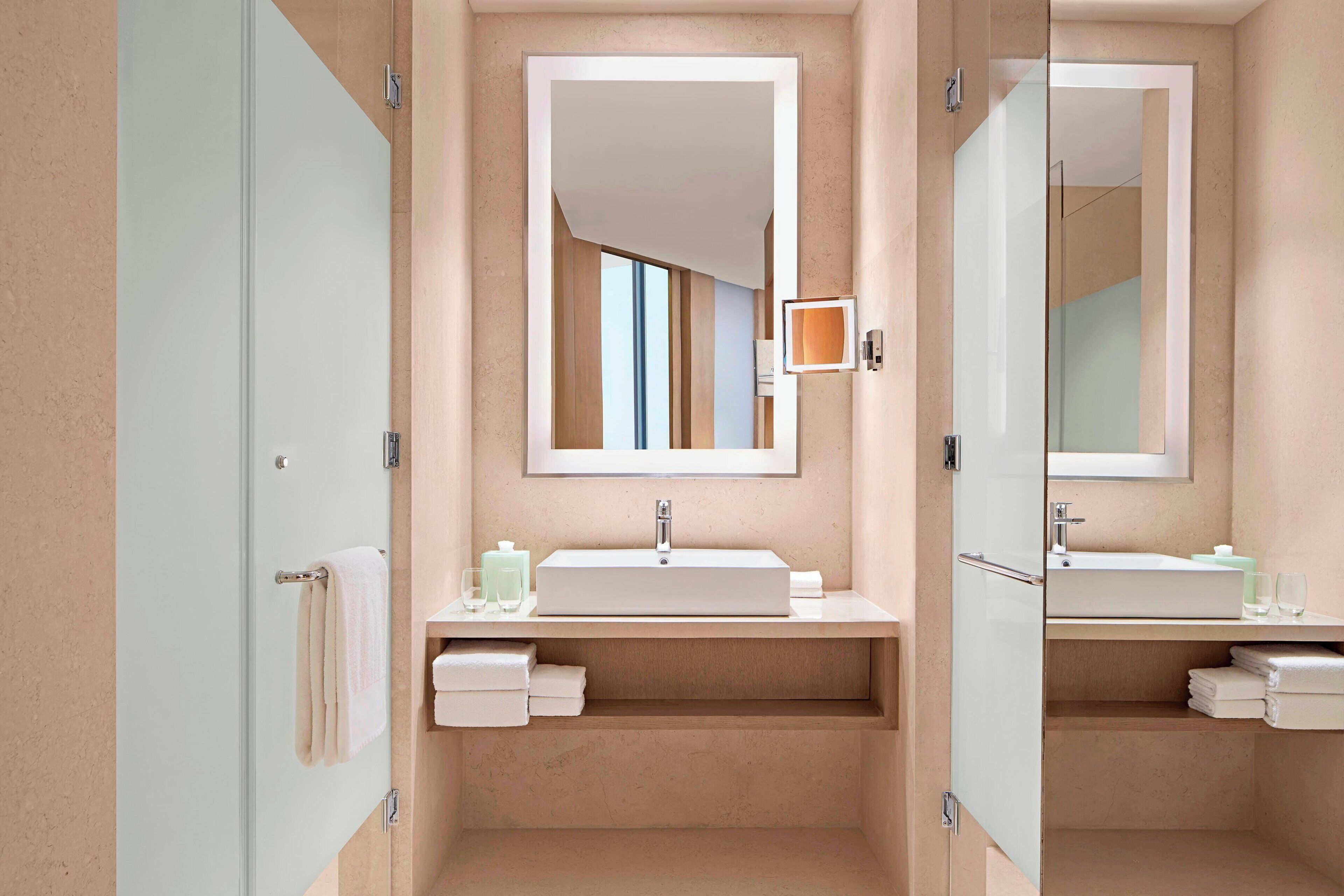 Un baño moderno con un espejo grande, un lavabo y una zona de ducha.