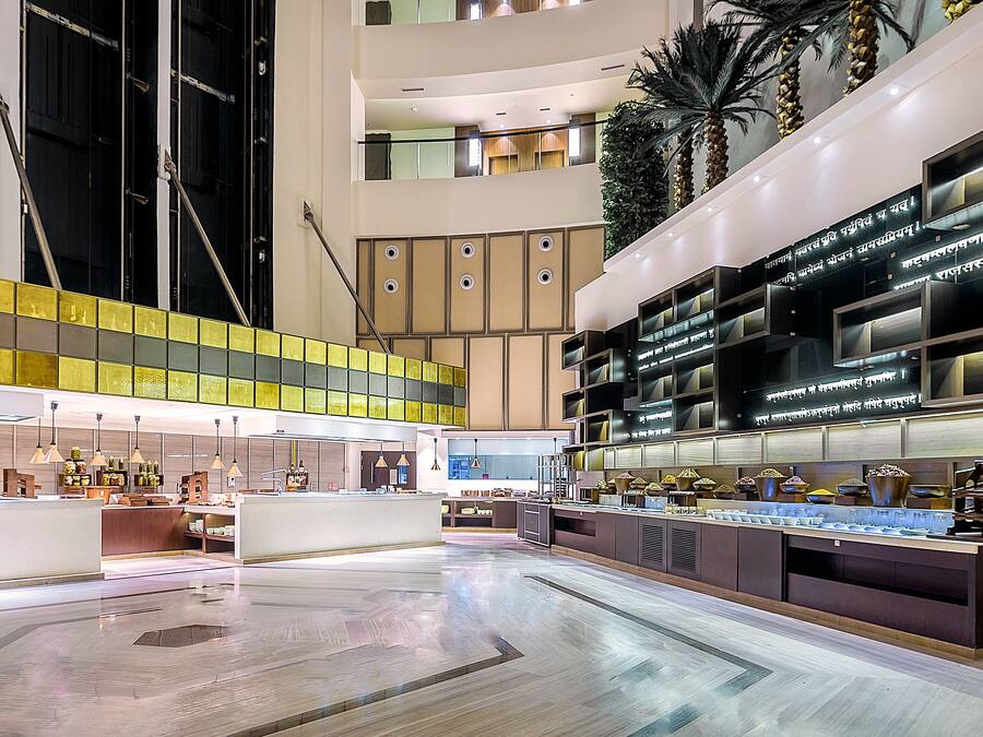 Un vaste atrium doté d’un haut plafond, avec un îlot central où sont exposés des objets, entouré d’espaces de détente et d’un escalier moderne.