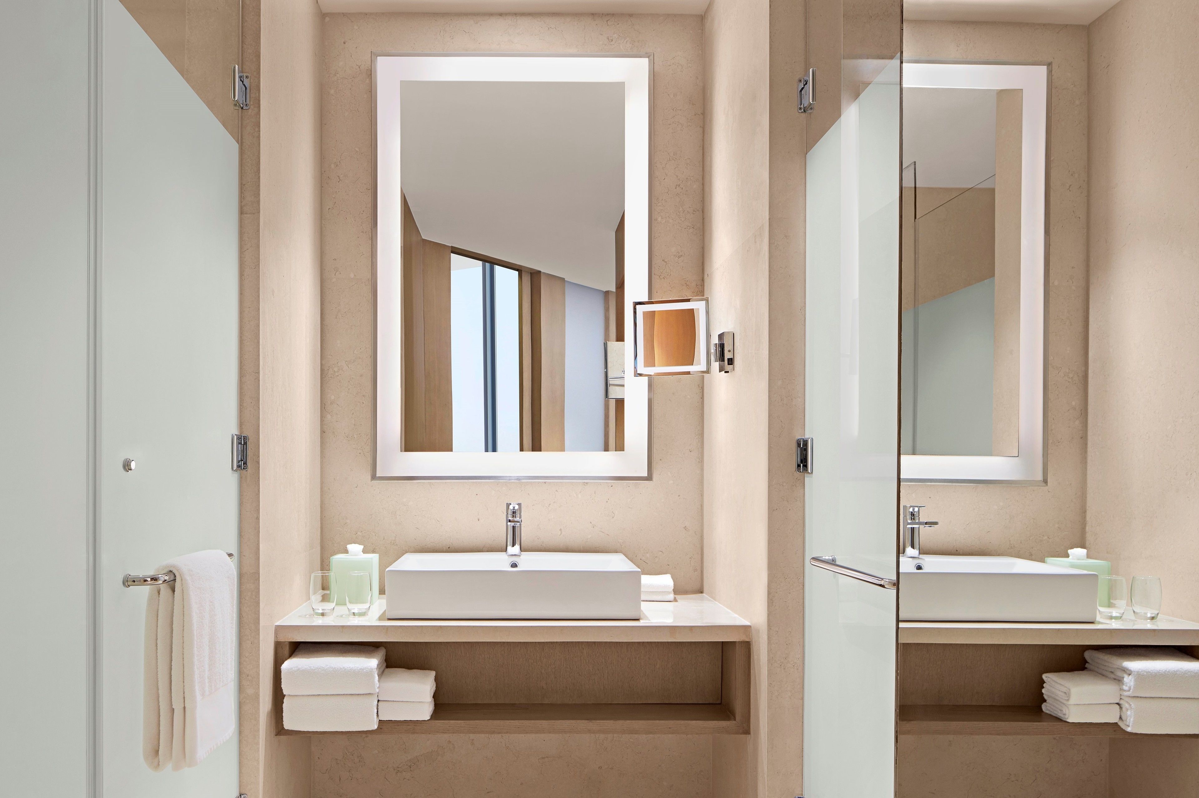 A modern bathroom with a large mirror, a rectangular sink, and a towel rack.