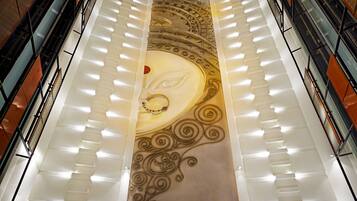 Un gran atrio con una escalera espiral central, diseños ornamentales en las paredes e iluminación moderna.