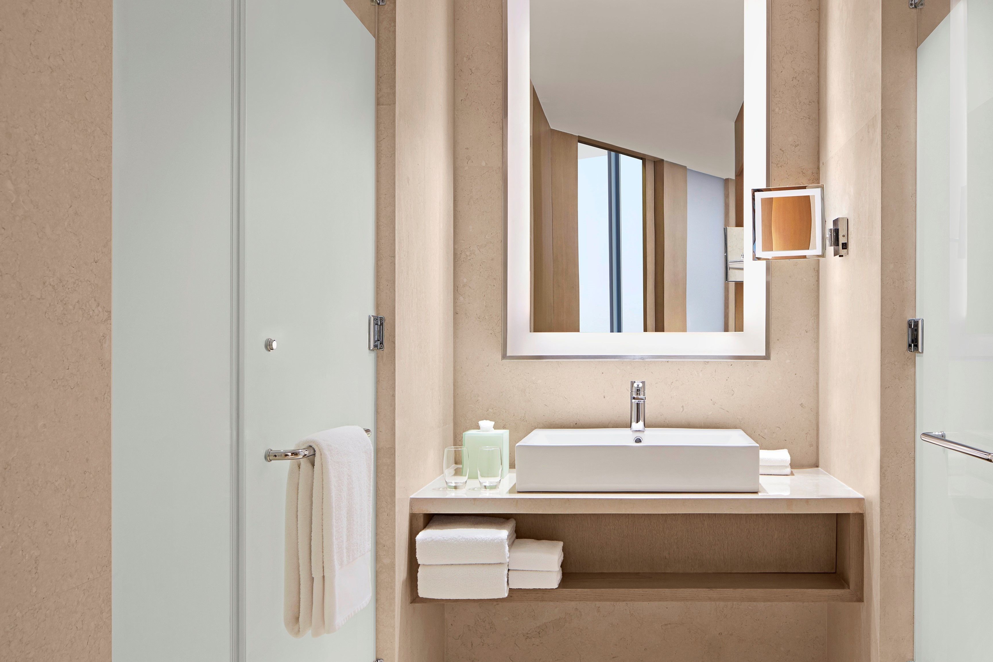 Un baño moderno con un espejo grande, un lavabo y un perchero para toallas.