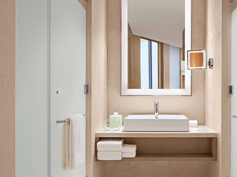 A modern bathroom with a large mirror, a sink, and a towel rack.