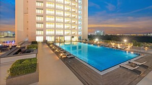 A rooftop pool with lounge chairs and a view of a high-rise building at dusk. - The Westin Kolkata Rajarhat (Barasat)