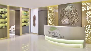 A modern spa reception area with a reception desk labeled "heavenly by Westin spa," shelves with various spa products, and a decorative tree wall.