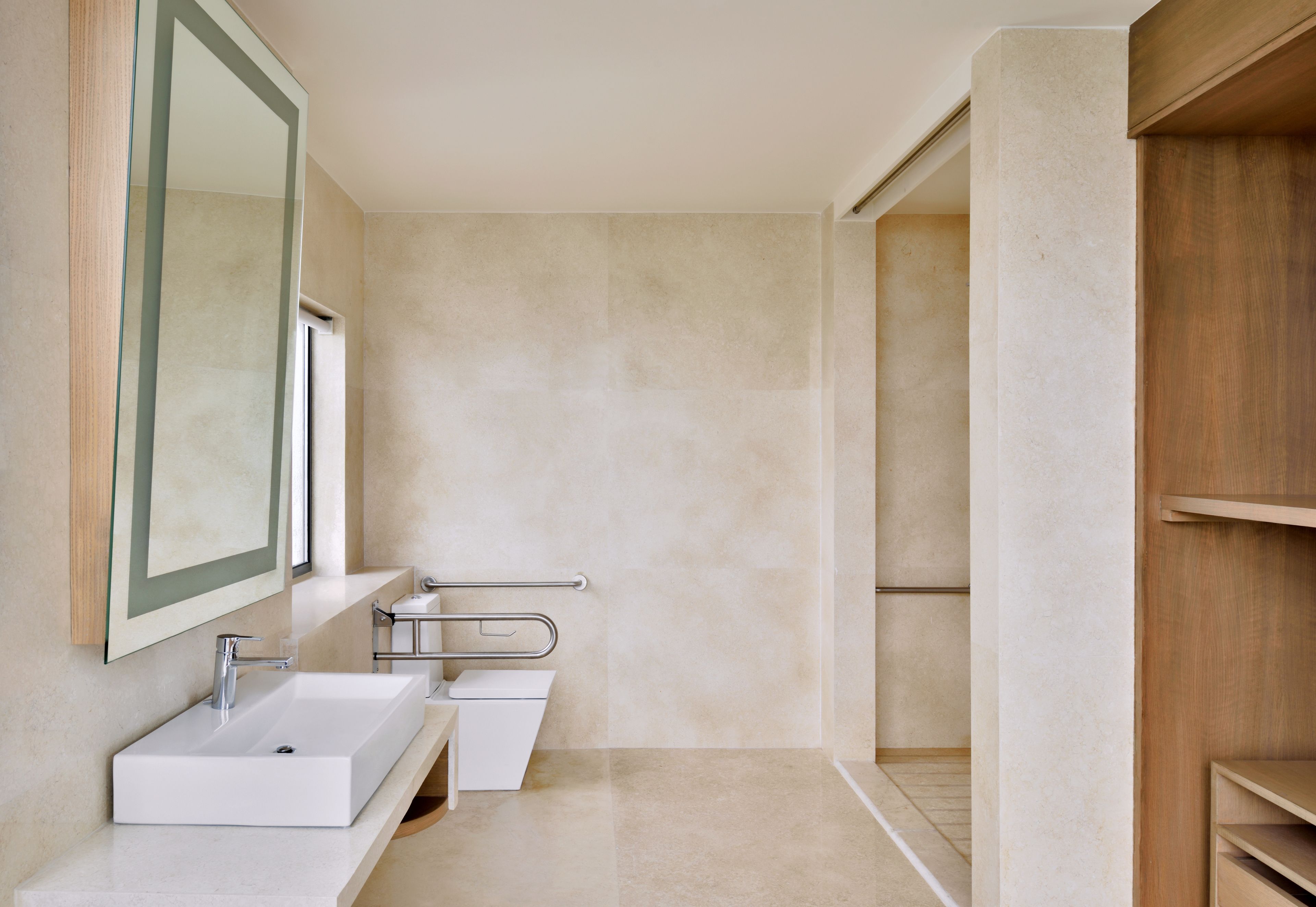 A modern bathroom with a large mirror, a white sink, and a shower area.