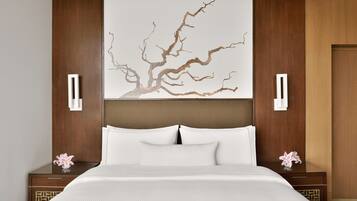 Habitació d'hotel moderna amb un llit gran, una obra decorativa a la paret i dues taules de nit amb làmpades.