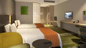 Moderni hotellihuone, jossa on sänky, työpöytä, tuoli ja televisio.