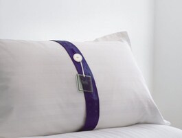 Almohada blanca con una banda morada y una etiqueta metálica.