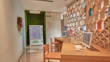 Un comptoir d’accueil avec un distributeur automatique, un ordinateur et une chaise.