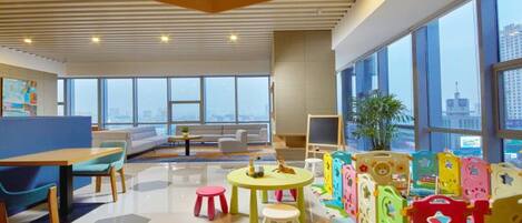 A modern office space with a high ceiling, large windows, and a view of the cityscape.
