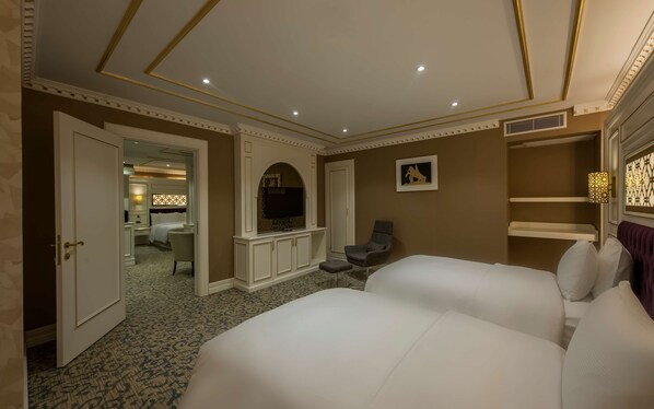 Habitación de hotel con una cama grande, televisión, silla y escritorio con computadora.