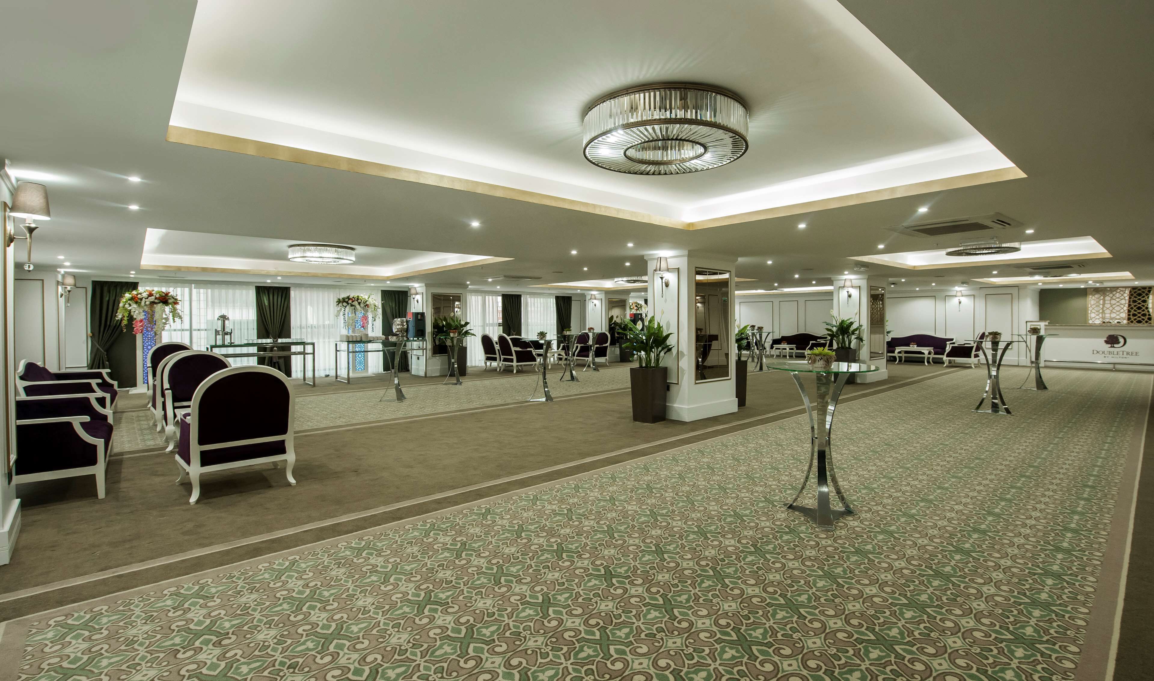 A spacious hotel lobby with a patterned carpet, seating areas, and a reception desk.