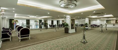 A spacious hotel lobby with a patterned carpet, seating areas, and a reception desk.