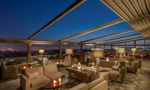 A rooftop lounge with sofas, tables, and lamps, offering a city view. - DoubleTree By Hilton Elazig (Elazig)