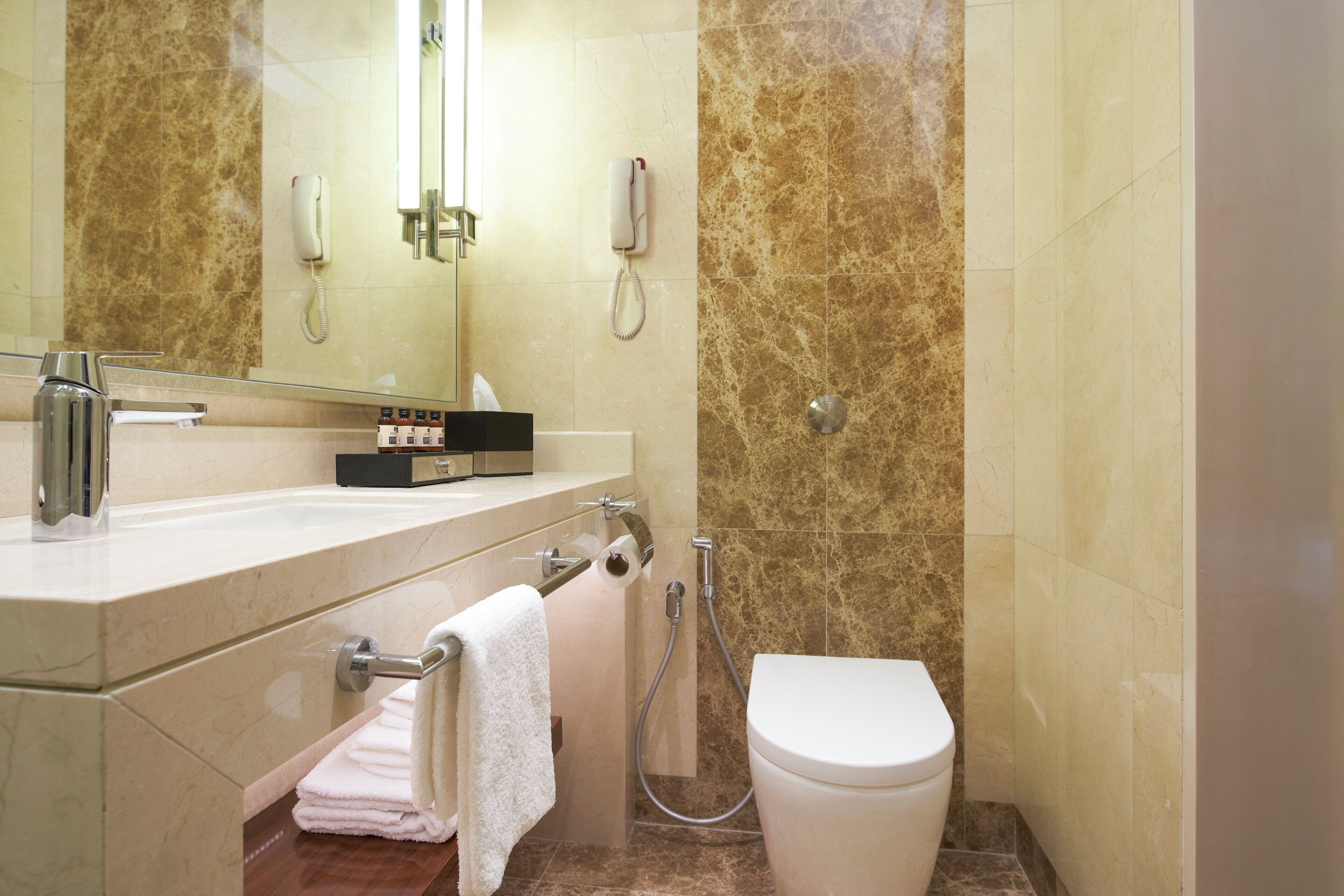 Un baño con inodoro, lavamanos, espejo y perchero para toallas.