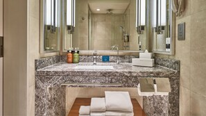 Une salle de bain avec un comptoir en marbre, un lavabo, un miroir, une douche et un porte-serviettes.