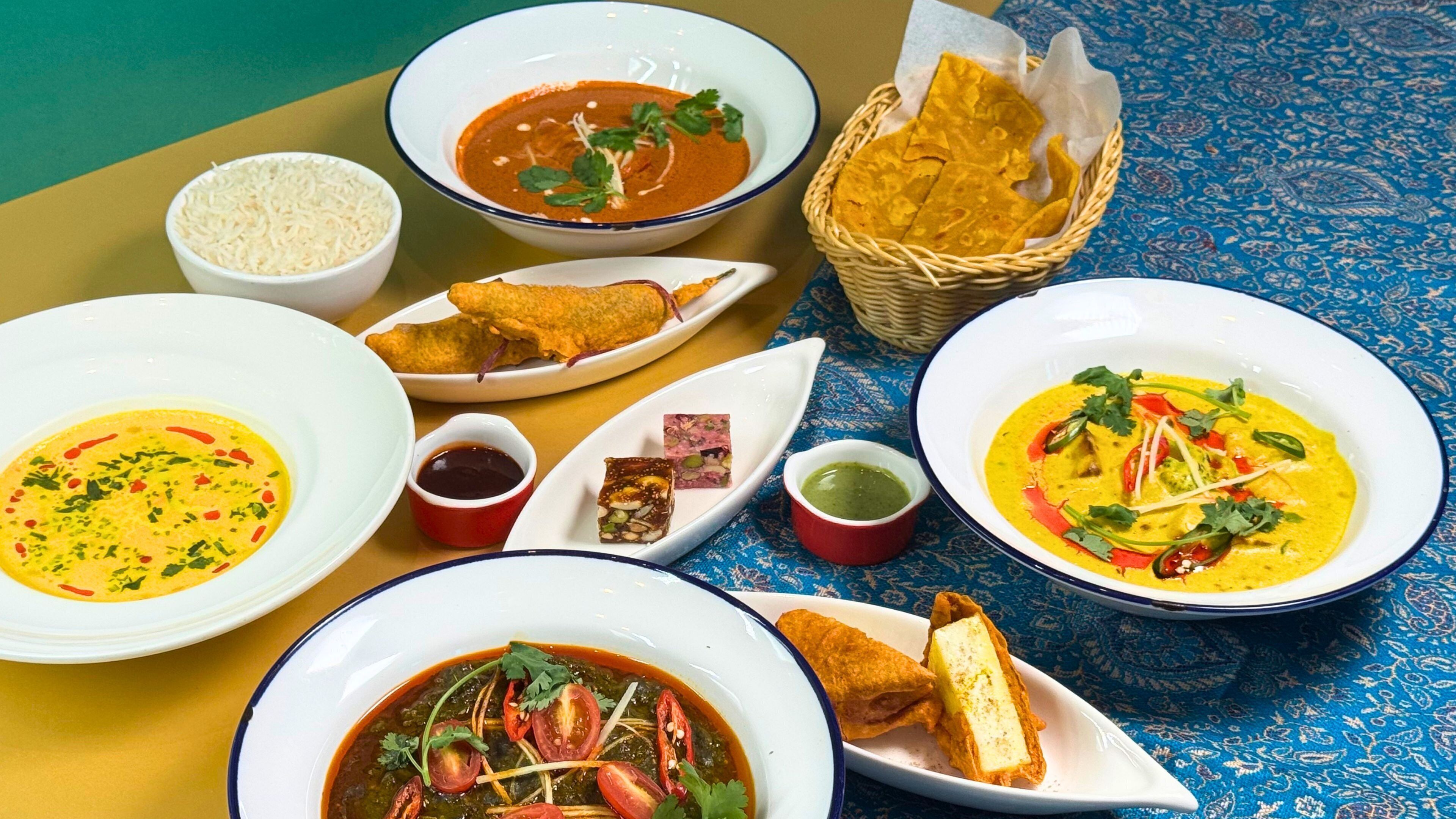 A table set with various dishes including soup, bread, and a basket of chips.