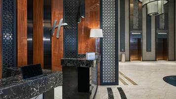 A modern reception desk with a marble top, a laptop, and a sign indicating 'IHG One Rewards'.