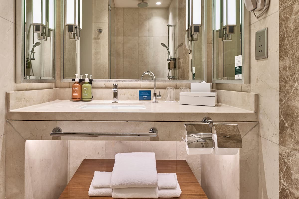 Un baño moderno con un espejo grande, un lavabo, una ducha y un perchero para toallas.