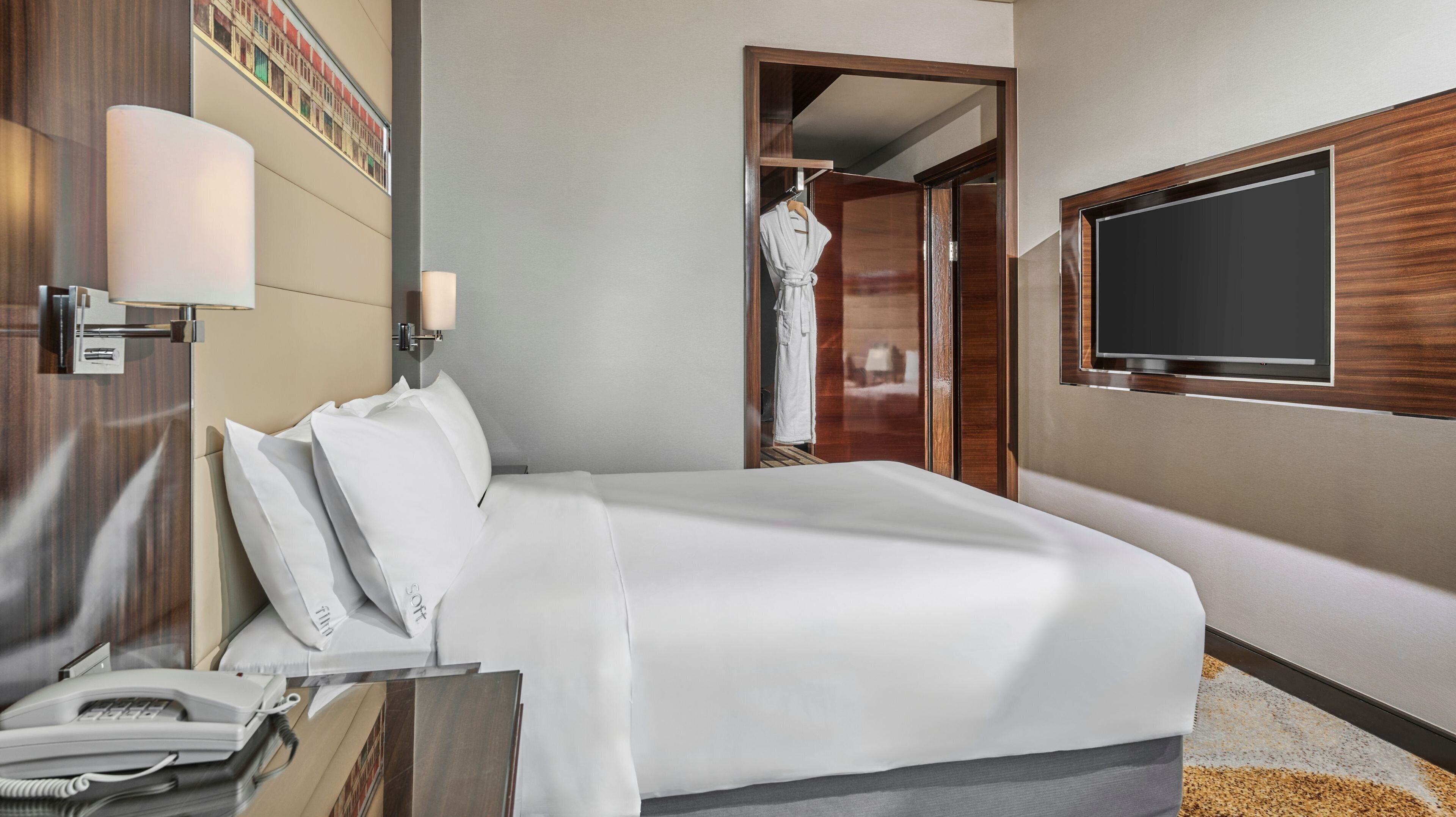 Ein Hotelzimmer mit Bett, Fernseher, Bademantel und Telefon.