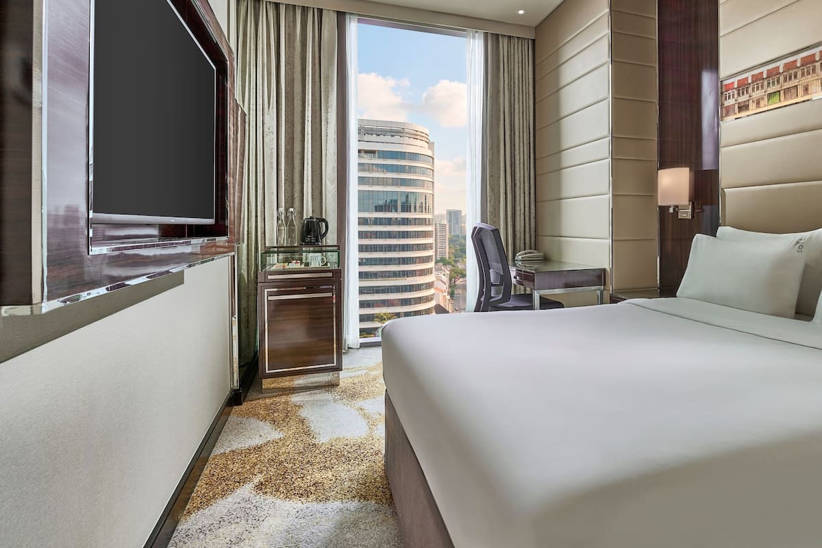 Habitación de hotel con cama, televisión, minibar, escritorio y vista a la ciudad.