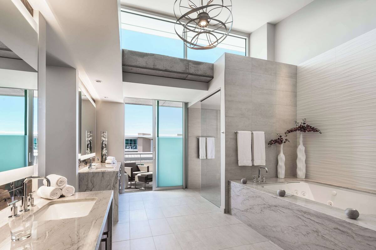 A modern bathroom with a large mirror, a bathtub, and a glass shower enclosure.