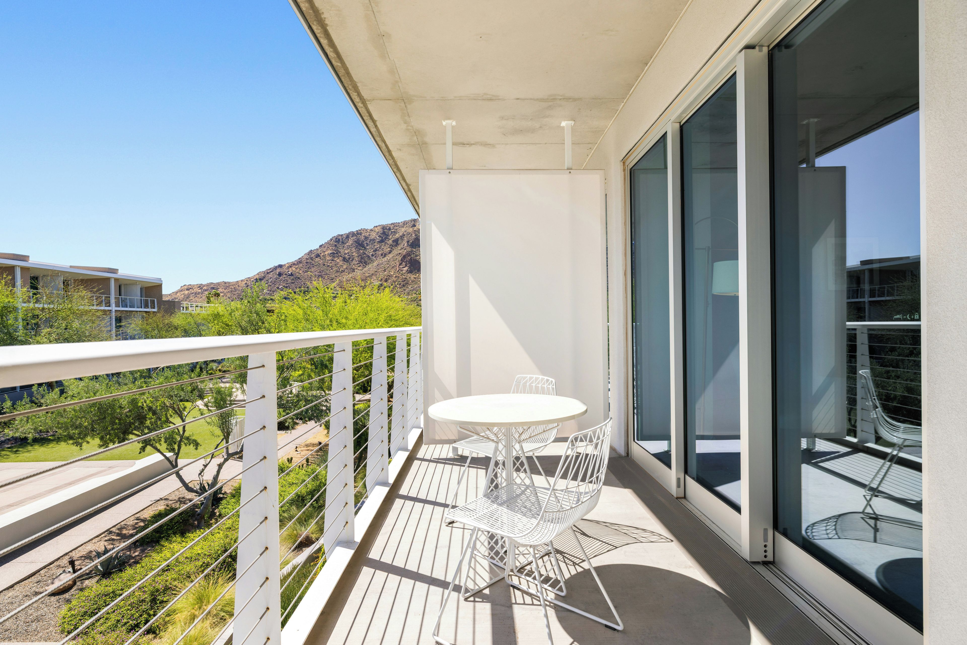 Un balcon avec une table et des chaises, une vue sur une montagne et un bâtiment en arrière-plan.