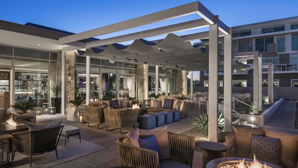 An outdoor seating area with fire pits and modern furniture, overlooking a cityscape.