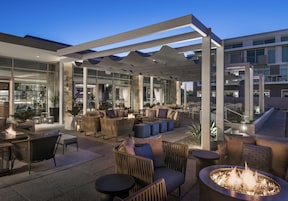 An outdoor seating area with fire pits and modern furniture, overlooking a cityscape.