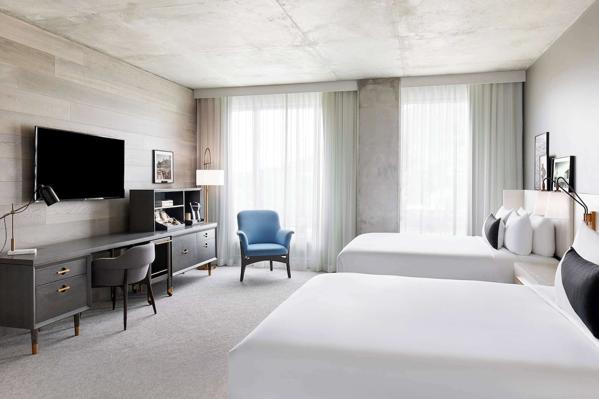 A hotel room with a large bed, a desk with a chair, a TV, and a window with curtains.
