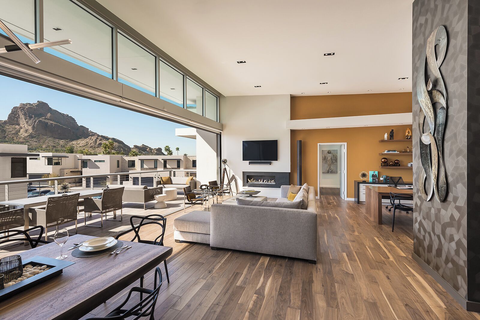 A spacious living area with a fireplace, a dining area with a wooden table, and a view of a mountainous landscape through large windows.