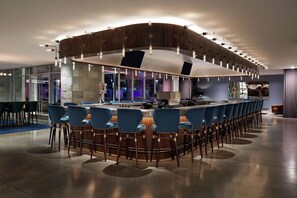 A modern bar area with a curved counter, blue bar stools, and ambient lighting. - Mountain Shadows Resort Scottsdale (Paradise Valley)