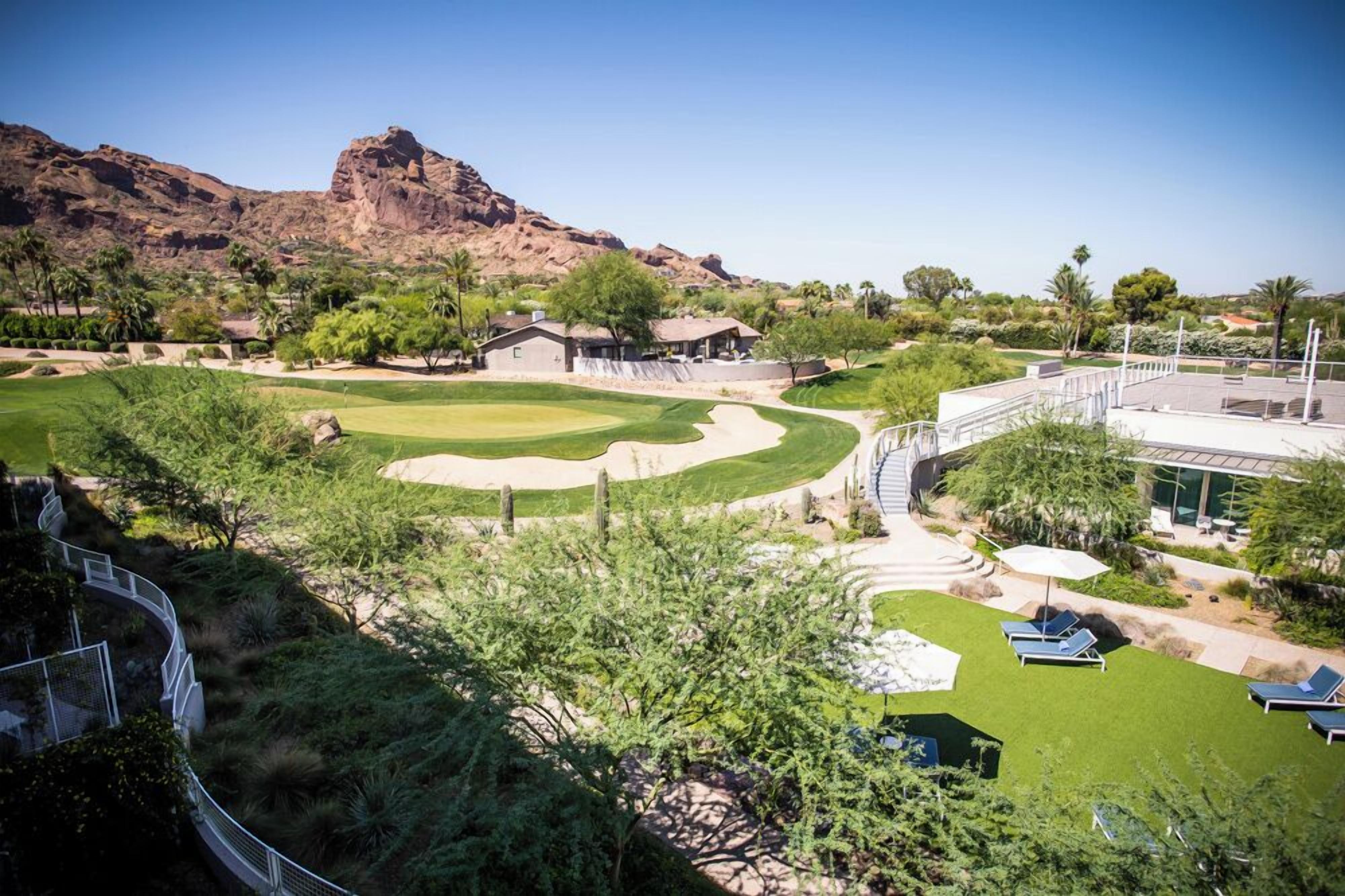 A golf course with a clubhouse, a pool area, and a desert landscape in the background.