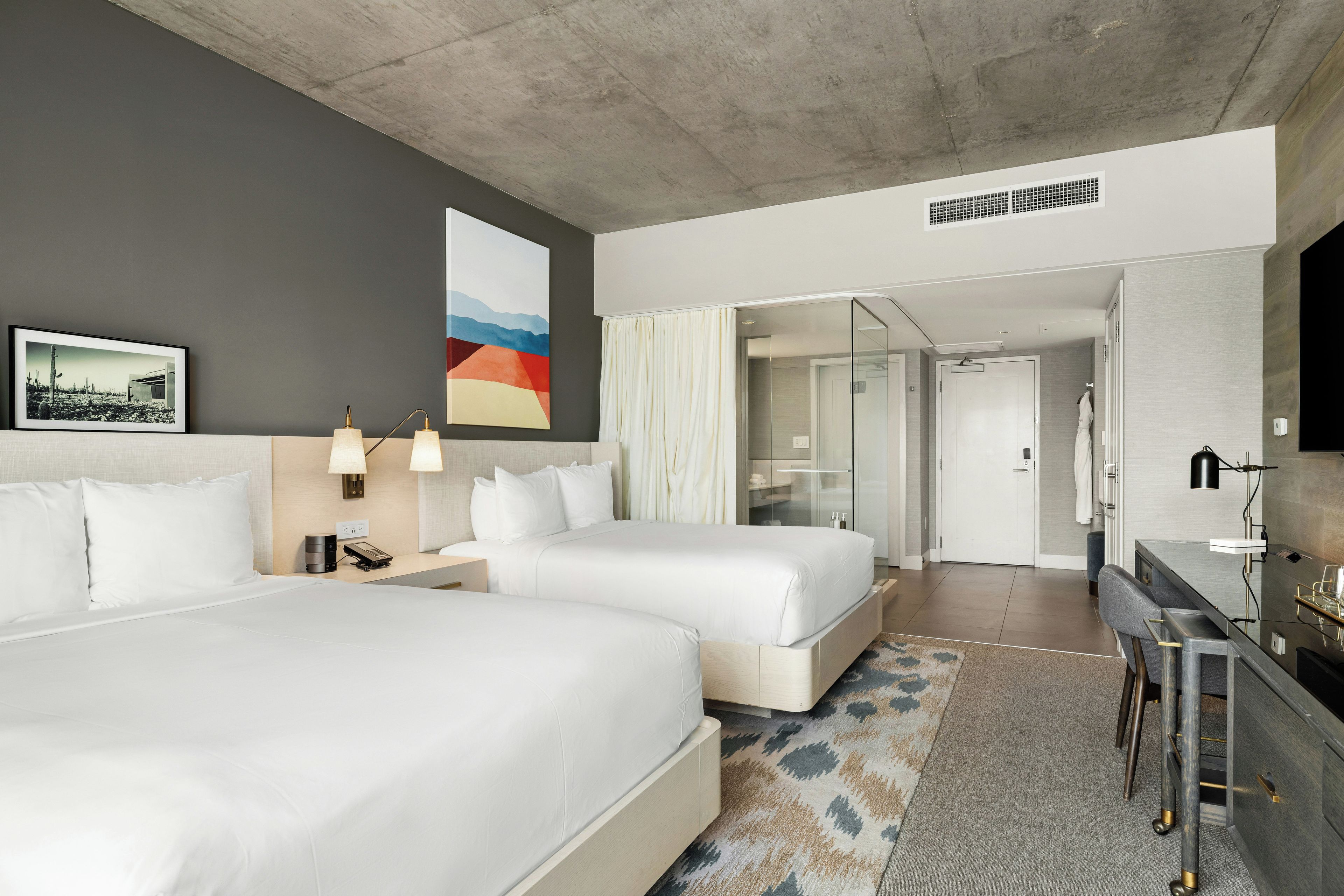 Une chambre d’hôtel avec deux lits, un bureau, une salle de bain et une vue sur le désert.