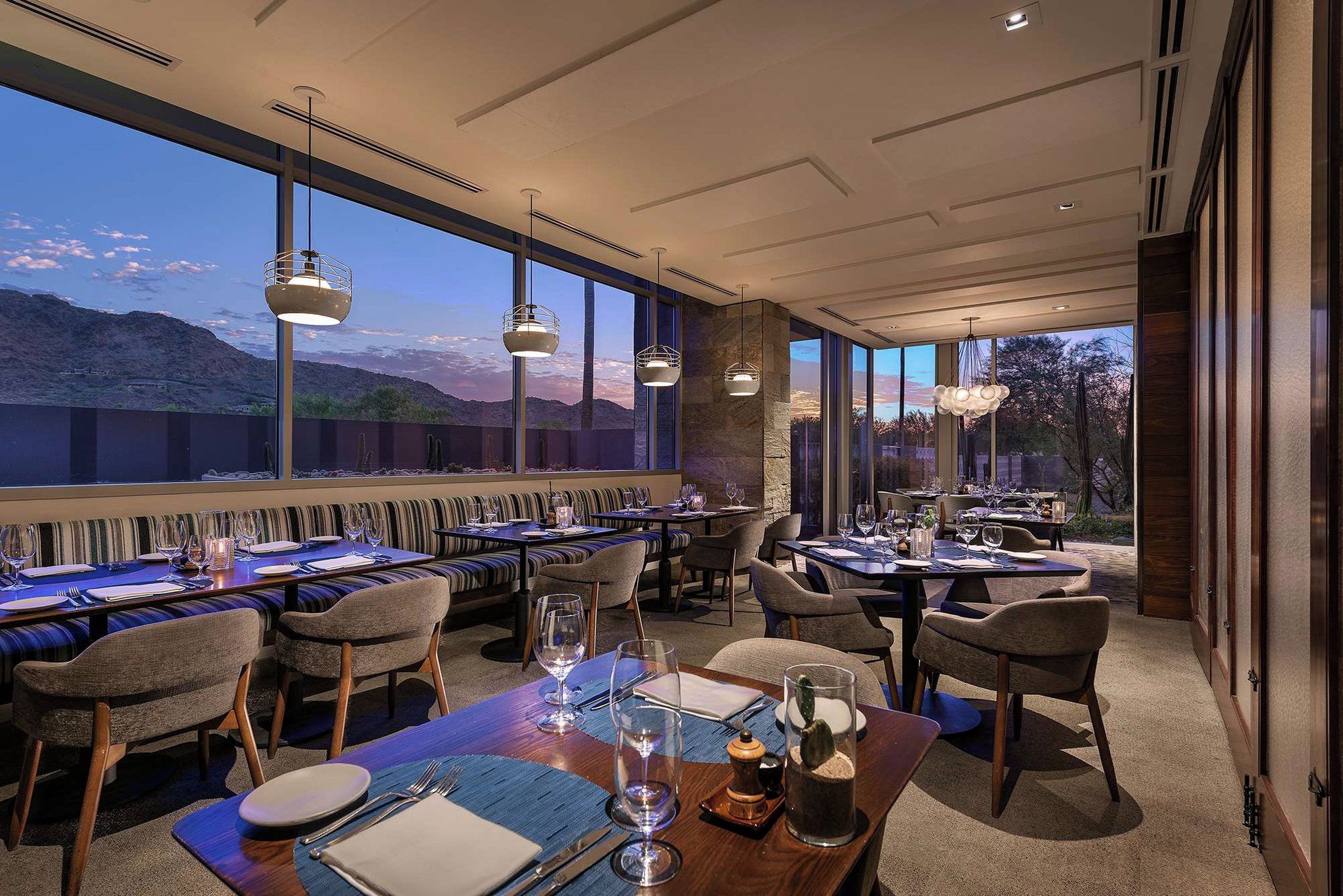 Un restaurant doté de nombreuses tables, de chaises et de luminaires suspendus.