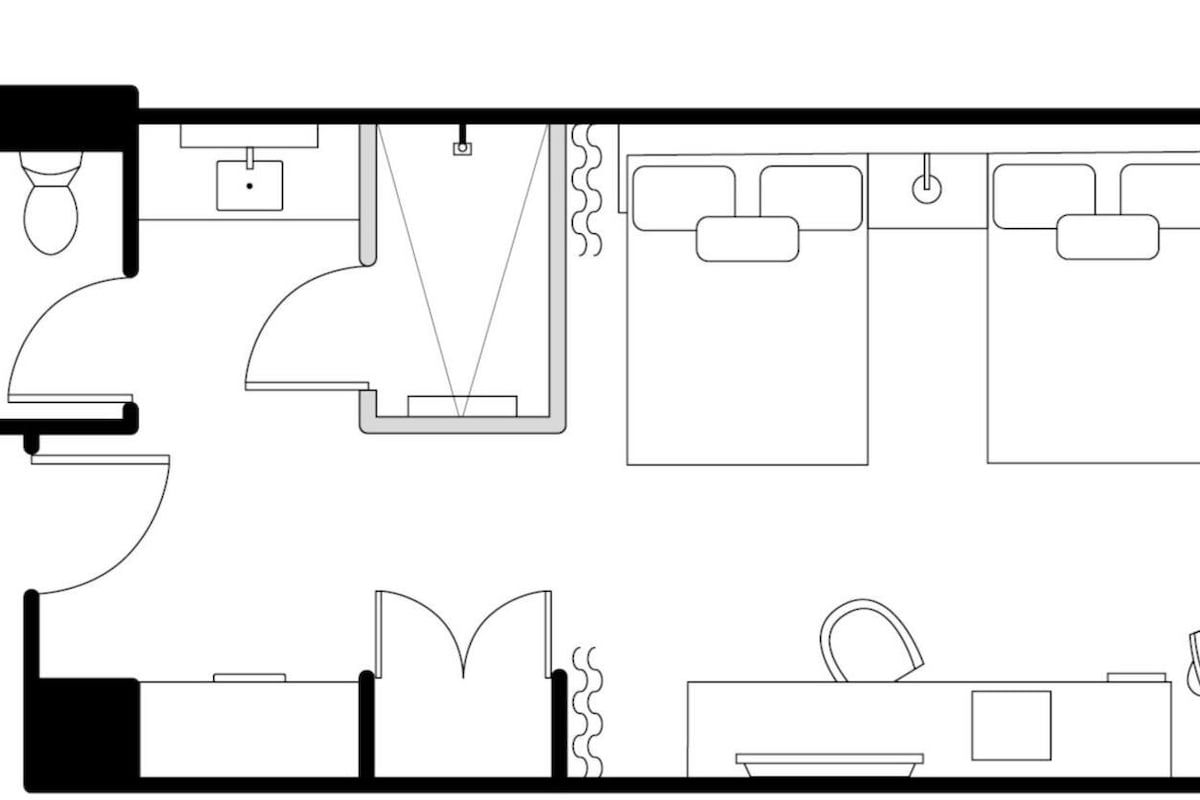 A hotel room layout with a bathroom, a kitchenette, a bed, and a seating area.