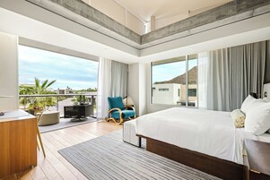 Un dormitorio moderno con una cama grande, un escritorio y una silla, que cuenta con un balcón con vistas al paisaje.