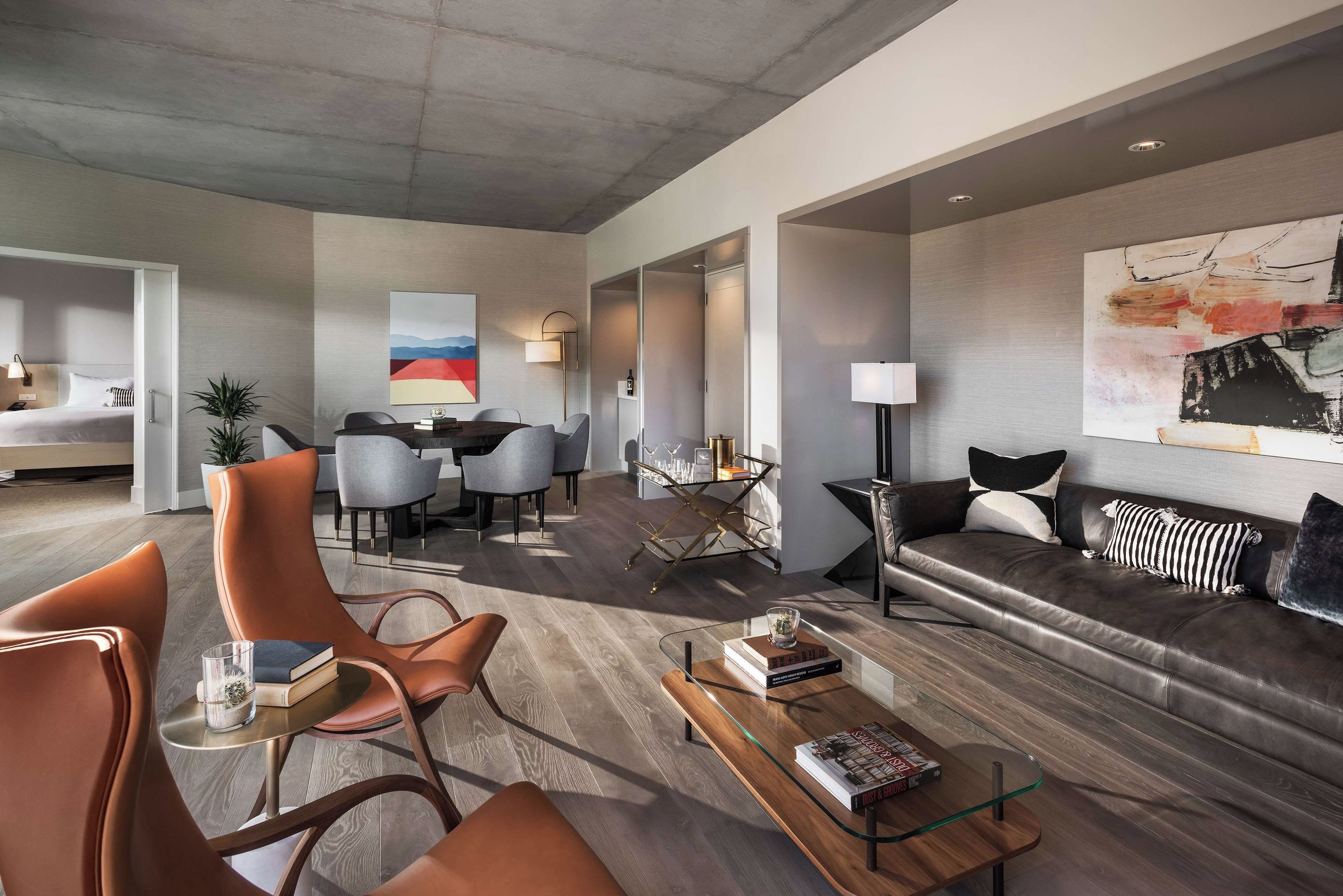 A modern living room with a sofa, chairs, a coffee table, and a dining area with a table and chairs.