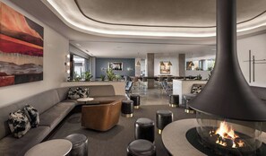 A modern lounge area with a fireplace, seating, and a dining area. - Mountain Shadows Resort Scottsdale (Paradise Valley)