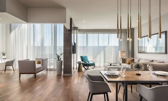 Uma sala de estar moderna com área de jantar, janelas amplas e escada.