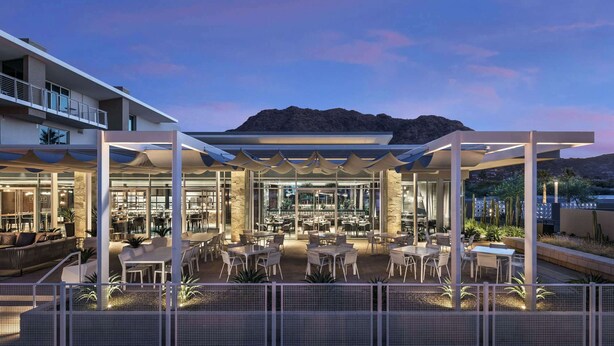 A modern outdoor dining area with tables and chairs, a covered seating area, and a view of a mountain in the background. - Mountain Shadows Resort Scottsdale (Paradise Valley)