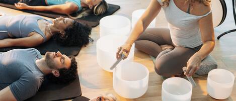 A group of people lying on mats in a room with large white bowls.