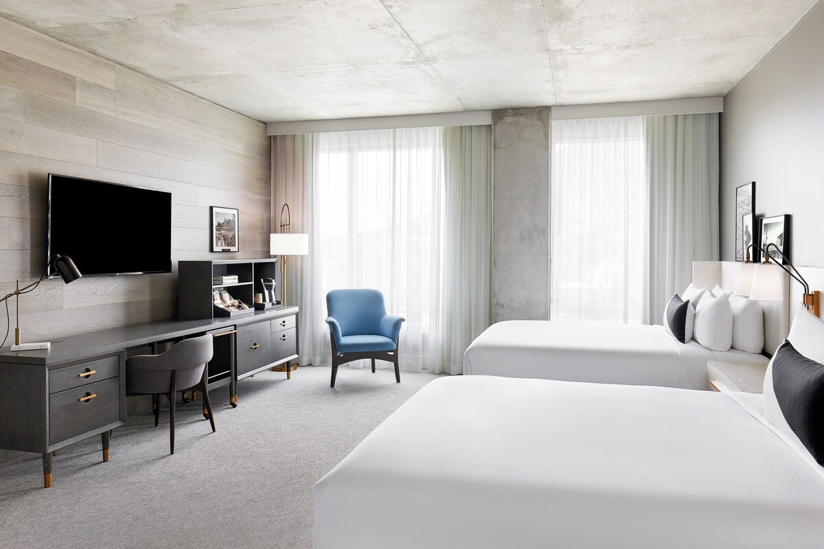A hotel room with a large bed, a desk, a chair, and a TV.