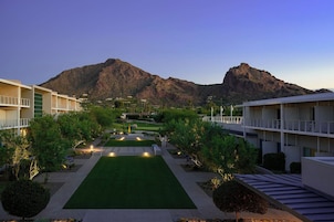 A hotel courtyard with a central lawn, surrounded by buildings and a mountain backdrop.
