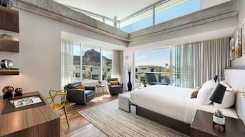 Ein modernes Hotelzimmer mit einem großen Bett, einem Schreibtisch und einem Balkon mit Blick auf die Stadt.