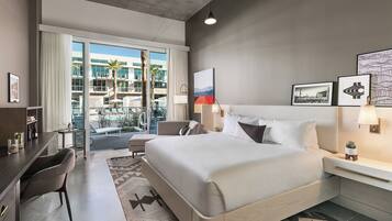Une chambre d’hôtel moderne avec un grand lit, un bureau et une vue sur une piscine et un immeuble.