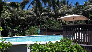 Una piscina envoltada de vegetació exuberant i palmeres.